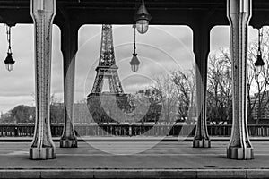 Grayscale shot of the Bir-Hakeim bridge with columns and the Eiffel Tower in the background, Paris.