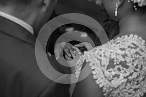 Grayscale shot of the bride and the groom putting rings