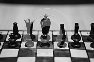 Grayscale shot of a chessboard with the focus on black\'s king, queen and pawns