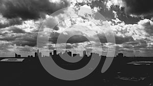 Grayscale shot of cityscape silhouette under the cloudy sky
