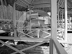 Grayscale shot of covered pavilions and wooden huts on the beach in Alacati Bay in Turkey