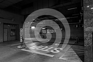 Grayscale shot of a deserted parking garage, featuring a long, wide expanse of concrete flooring