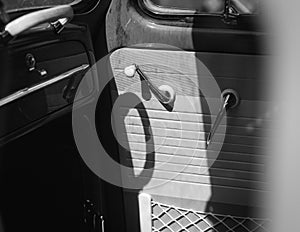 Grayscale shot of the front side door with handles and cases of a vintage classic car from inside
