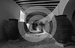 Grayscale shot of giant ancient pitchers in an old architecture hallway