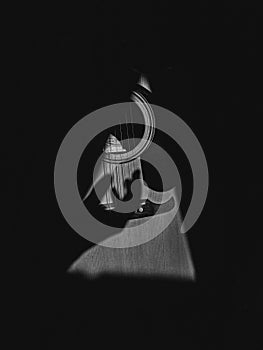 Grayscale shot of a hand shadow strumming on guitar strings