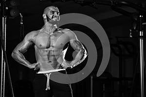 Grayscale shot of a healthy young Caucasian man posing in the gym and flexing his muscles