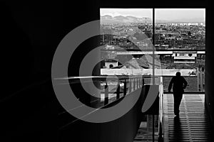 Grayscale shot of a man going down the stairs of a building