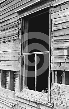 Grayscale shot of a rusty broken window in old wooden wall, side view shot