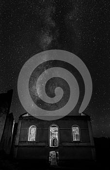 Grayscale shot of a sky full of stars above the house