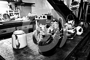 Grayscale shot of a traditional kitchen, with a variety of colorful kettles and pots