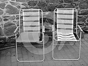 Grayscale shot of two folding chairs on the pavement outdoors