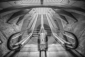 Grayscale shot of an underground escalator