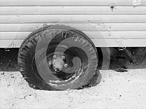Grayscale shot of a van's leaked tire