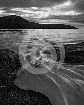 Grayscale shot of water flowing through rocks at Ettalong Beach in NSW, Australia