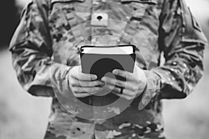 Grayscale shot of a young soldier holding a bible