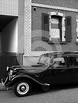 Grayscale vertical shot of a black French gangster limousine of the thirties and forties