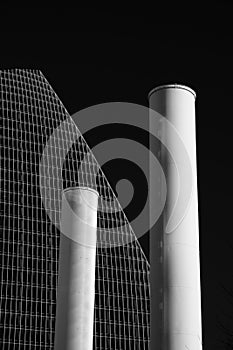 Grayscale vertical shot of two chimneys of a building isolated on black background