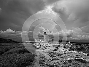 Grayscale view of a human walking toward the Faro Los Morrillos under the cloudy sky photo