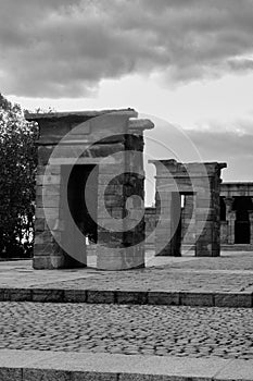 Grayscale view of a rocky gate of the Temple of Debod in Madrid, Spain against a cloudy gray sky