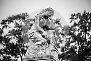 Grayscale view of a sad angel statue in Loudon Park Cemetery in Baltimore, Maryland photo