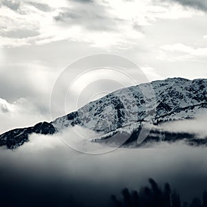 Grayscale view of the snowy Steinbergstein Mountain on a foggy day in the Kitzbuhel Alps, Austria