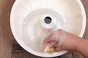 Greasing cake pan with margarine or butter.