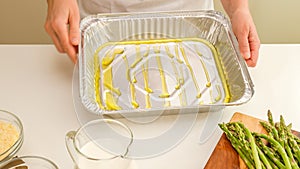 Greasing disposable baking pan with olive oil.