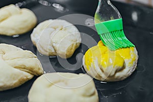 Greasing round dough close up. Round dough for a fancy cake greasing by green brush.