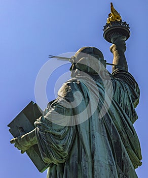 Great back photo of the Statue of Liberty holding her torch on a sunny day in Manhattan.