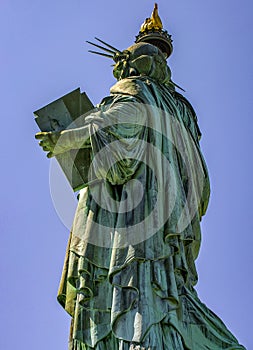 Great back vertical photo of the Statue of Liberty holding her torch on a sunny day in Manhattan.