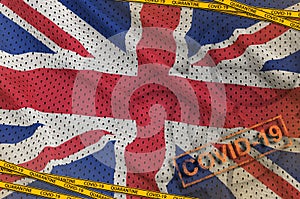 Great britain flag and Covid-19 biohazard symbol with quarantine orange tape and stamp. Coronavirus or 2019-nCov virus concept