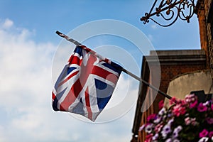 Great Britain flag on the house with flowers. State flaf with blue sky and clouds in the background. photo