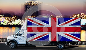 Great Britain flag on the side of a white van against the backdrop of a blurred city and river. Logistics concept