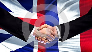 Great Britain and France handshake, international friendship, flag background