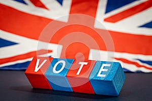 Great Britain vote, the word Vote on wooden blocks against the background of the British flag, the concept of voting and taking