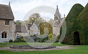 Great Chalfield Manor near Bradford on Avon, Wiltshire, UK, photographed from the garden with the church behind a yew tree.