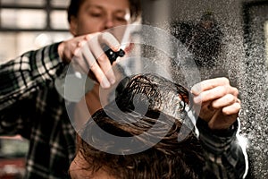 great close-up of head hair of male client which barber wets by spray and combs