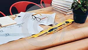 Great designs come from this desk. Still life shot of a pair of spectacles placed on top an architects blueprints in a