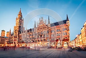 Great evening view of Marienplatz - City-center square & transport hub with towering St. Peter`s church, two town halls and a toy