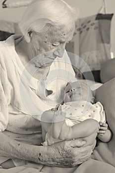 Great-grandmother holds in arms her great-grandson