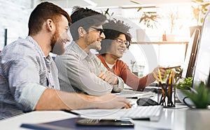 Three men enjoying good coding job on computer at modern office