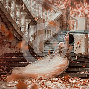 Great-looking charming dark-haired brunette girl sitting alone on the stone steps of an amazing royal castle, pretty