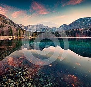 Great morning view of Fusine lake. Colorful autumn sunrise in Julian Alps with Mangart peak on background, Province of Udine,