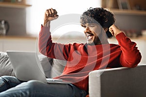 Great News. Happy Excited Indian Man Celebrating Success With Laptop At Home