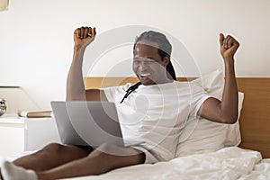 Great News. Joyful African American Man Celebrating Success With Laptop In Bed