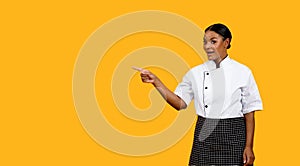 Great Offer. Excited Black Female Chef In Uniform Pointing At Copy Space