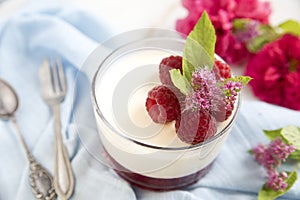Great panacotta dessert with raspberries, on a blue background and vintage spoon and fork. photo