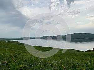 Great panoramic view. A clean mountain lake in the midst of majestic mountains in a haze of fog. On the Sunset. Copy photo