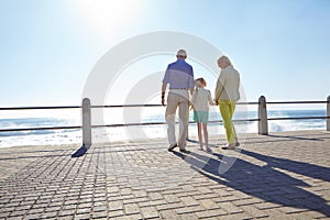 Great parents get promoted to grandparents. grandparents walking hand in hand with their granddaughter on a promanade.