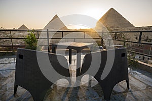 Great Pyramids of Chephren Khafra and Cheops Khufu and Mikerina Menkaura. Sunset on Giza plateau. sun sets below horizon. rooftop